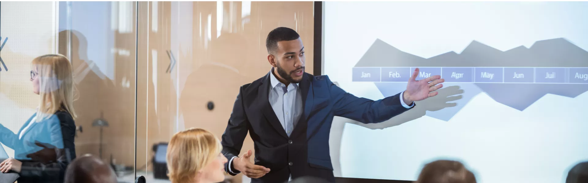Imagem de um homem falando com um grupo de pessoas apontando para um quadro