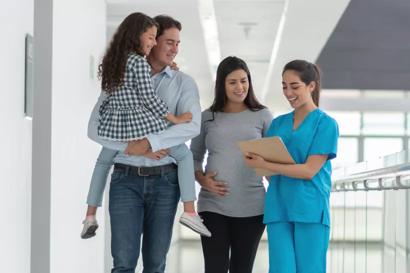 Um casal com sua filha, falando com uma médica